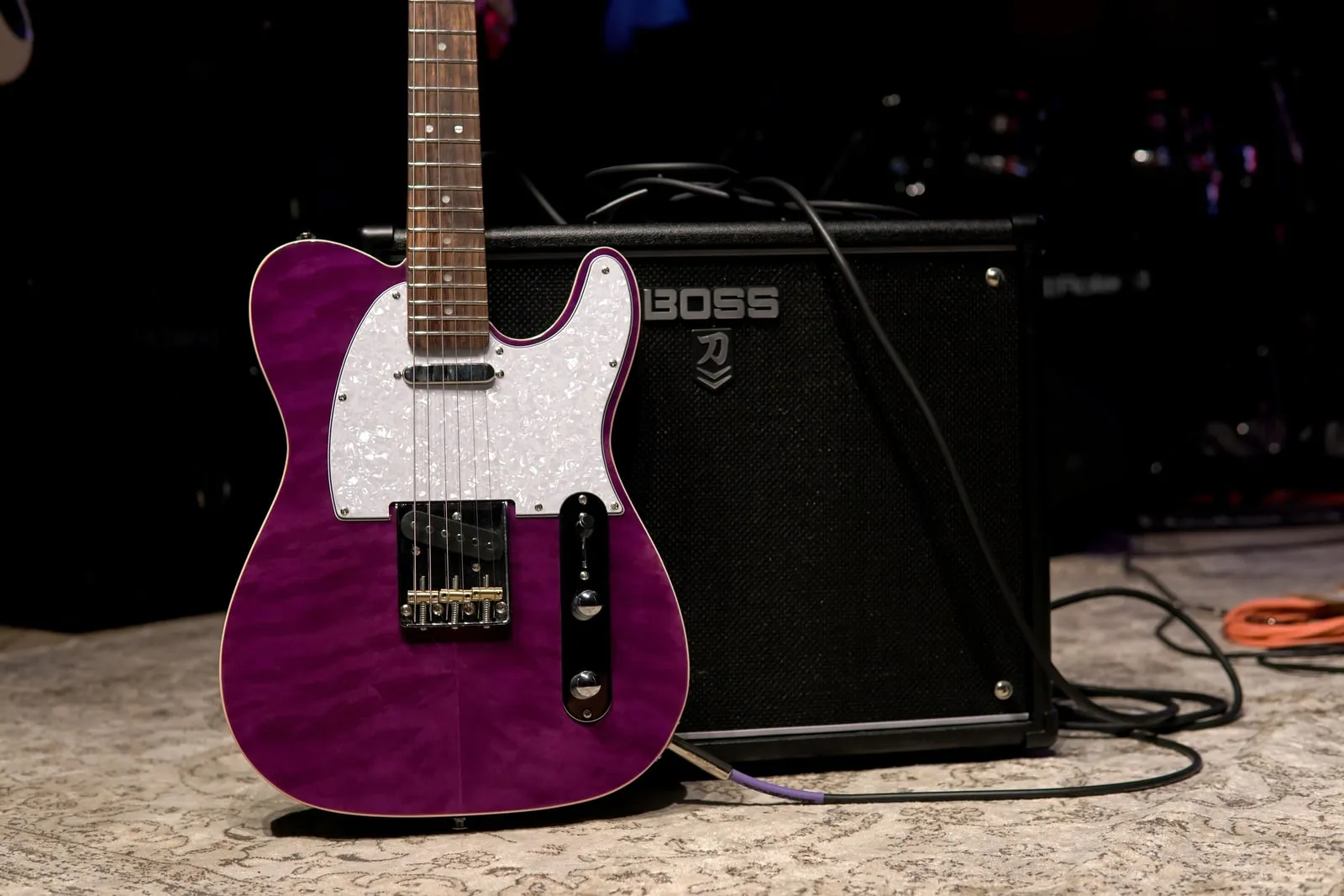 A purple electric guitar leaning against a combo amplifier