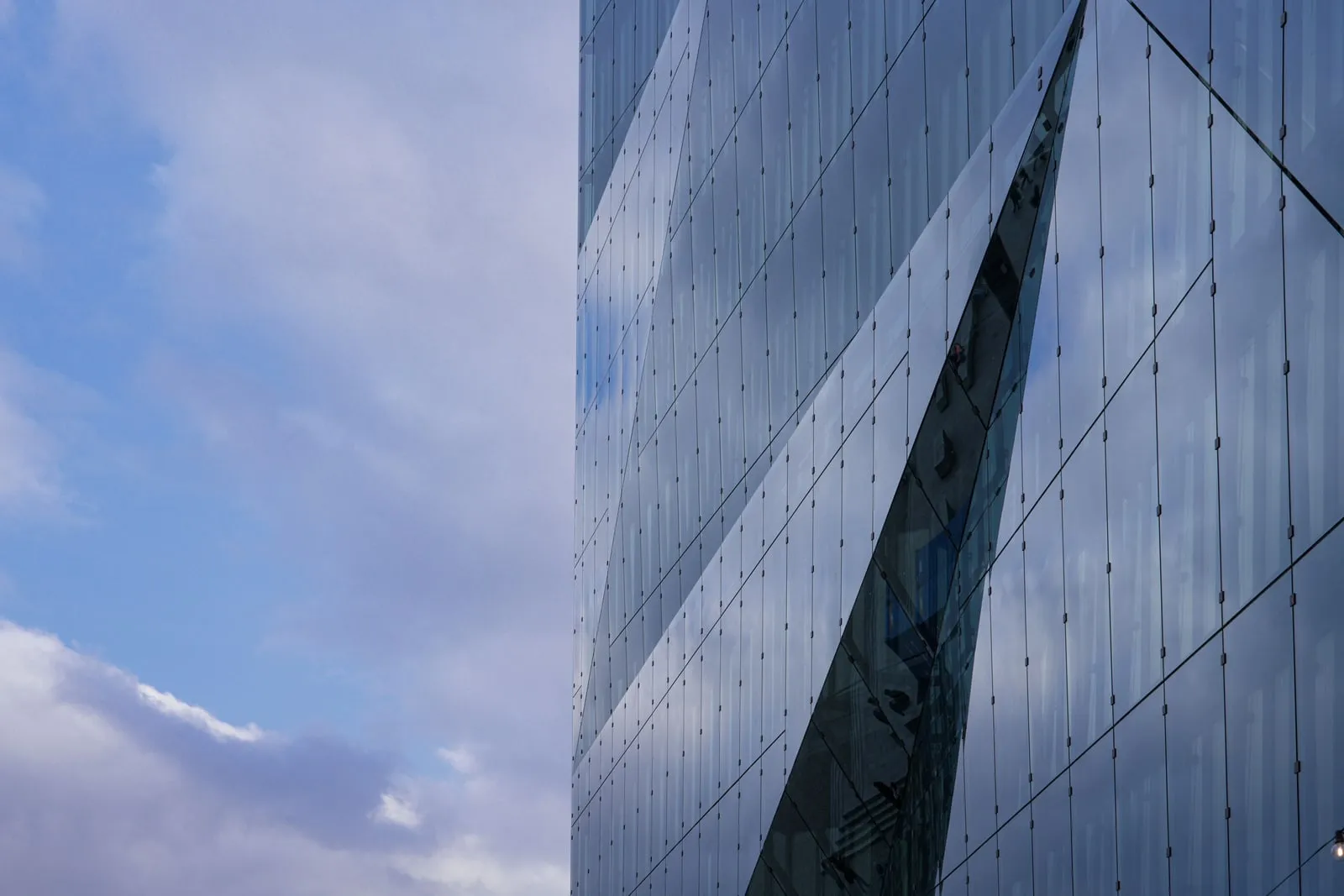 The glass facade of an office tower reflecting the sky