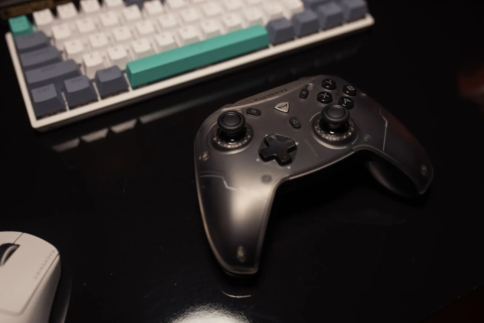 Un mando de videojuego apoyado en un escritorio junto a un teclado