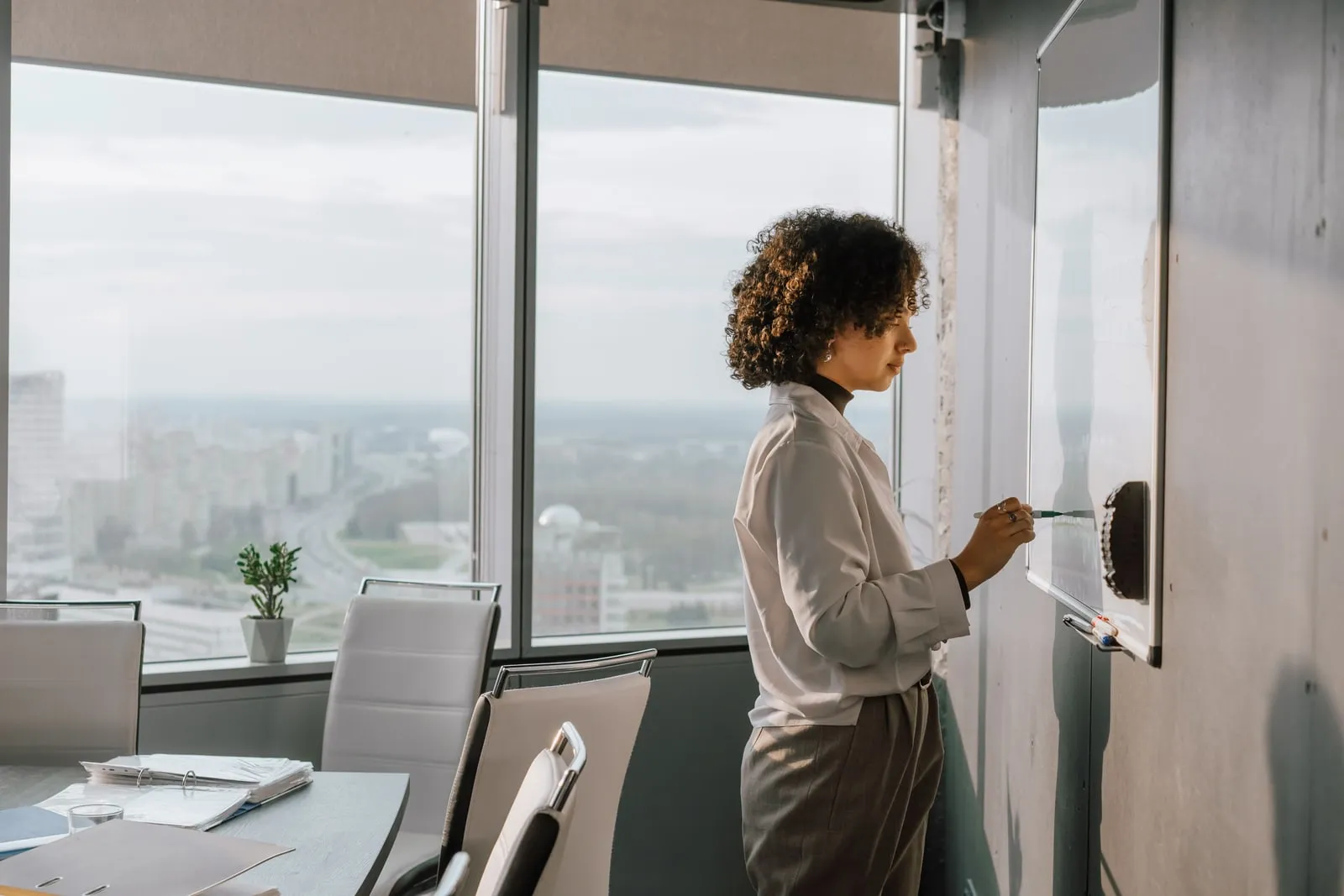 A person writing on a whiteboard in a meeting room