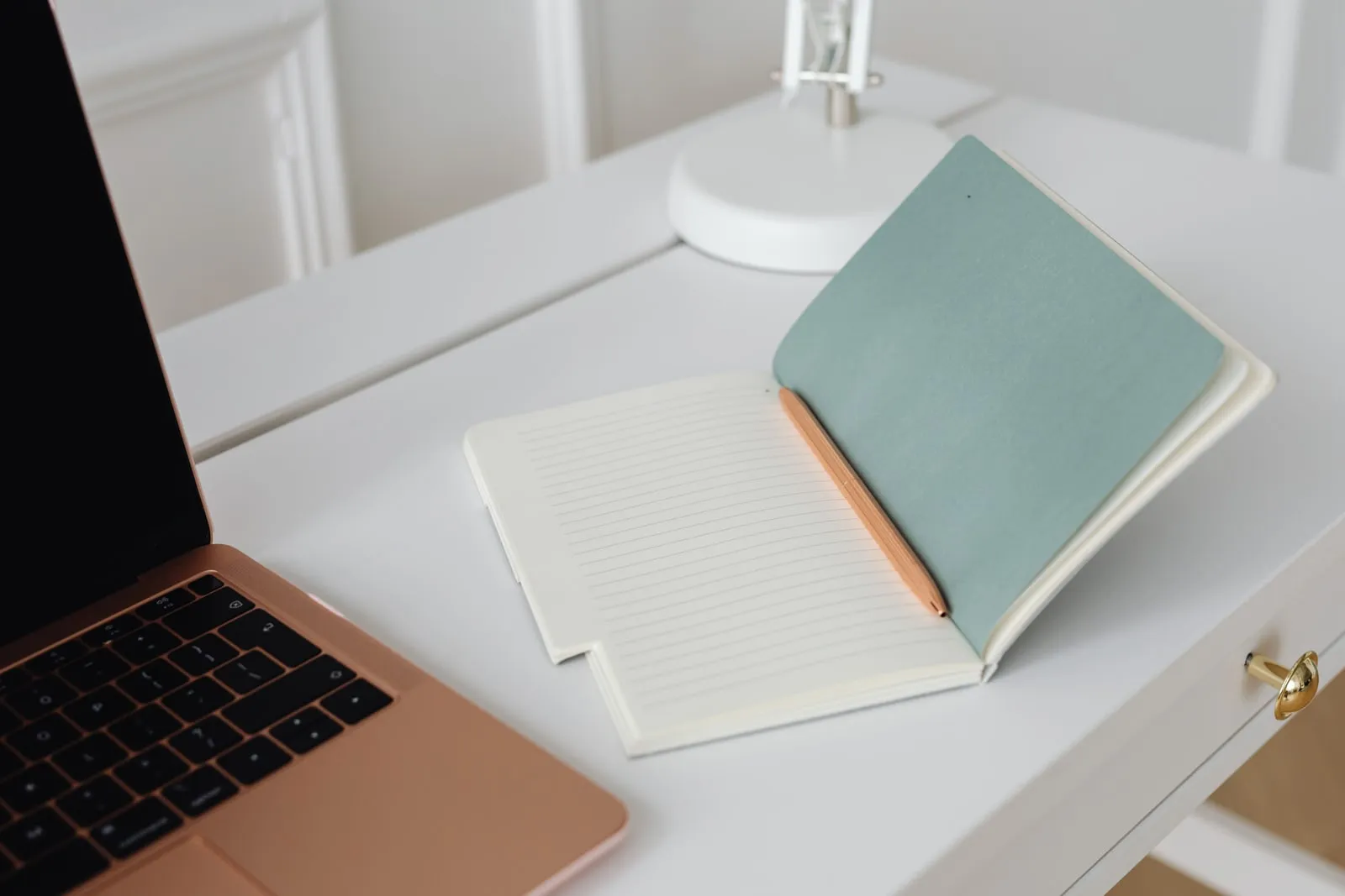 An open notebook and pen beside a laptop