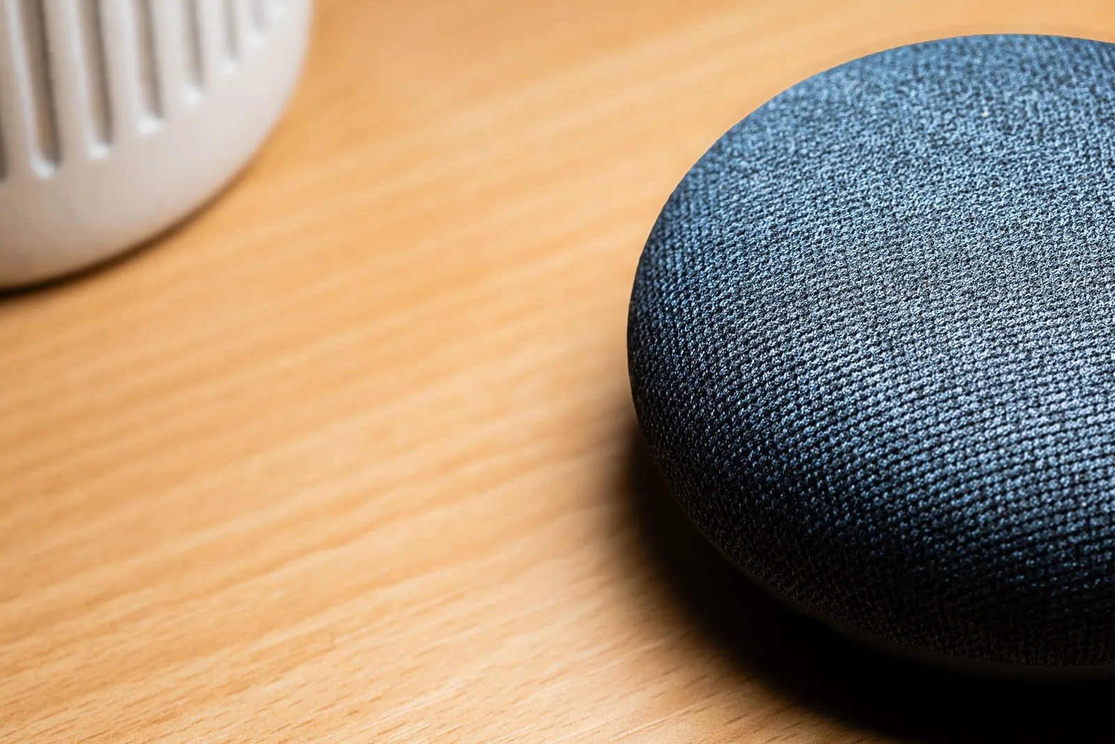 Two fabric-covered smart speakers on a wooden surface