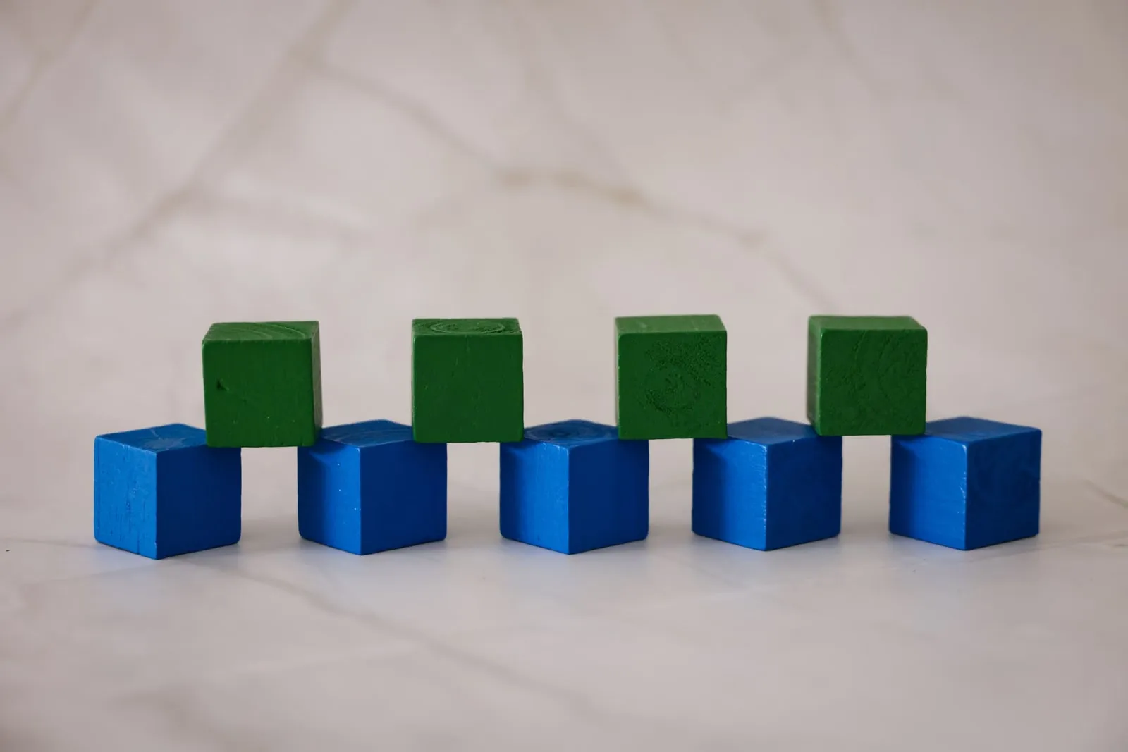 Blue and green wooden cubes arranged on a pale surface