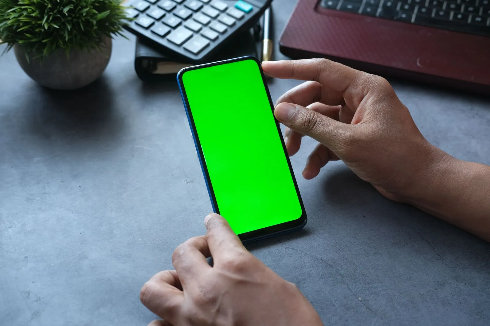 A person holding a smartphone at a desk.