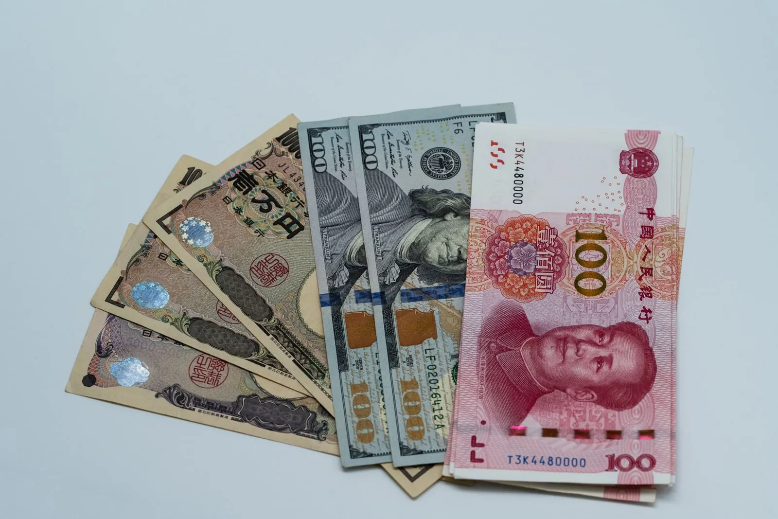 Chinese yuan, Japanese yen and US dollar banknotes fanned out on a white surface