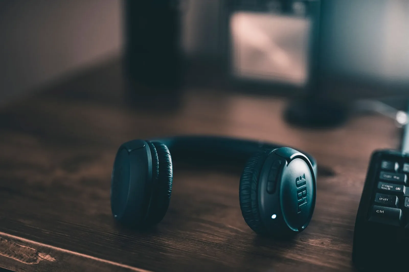 Unos auriculares inalámbricos de diadema apoyados en un escritorio de madera