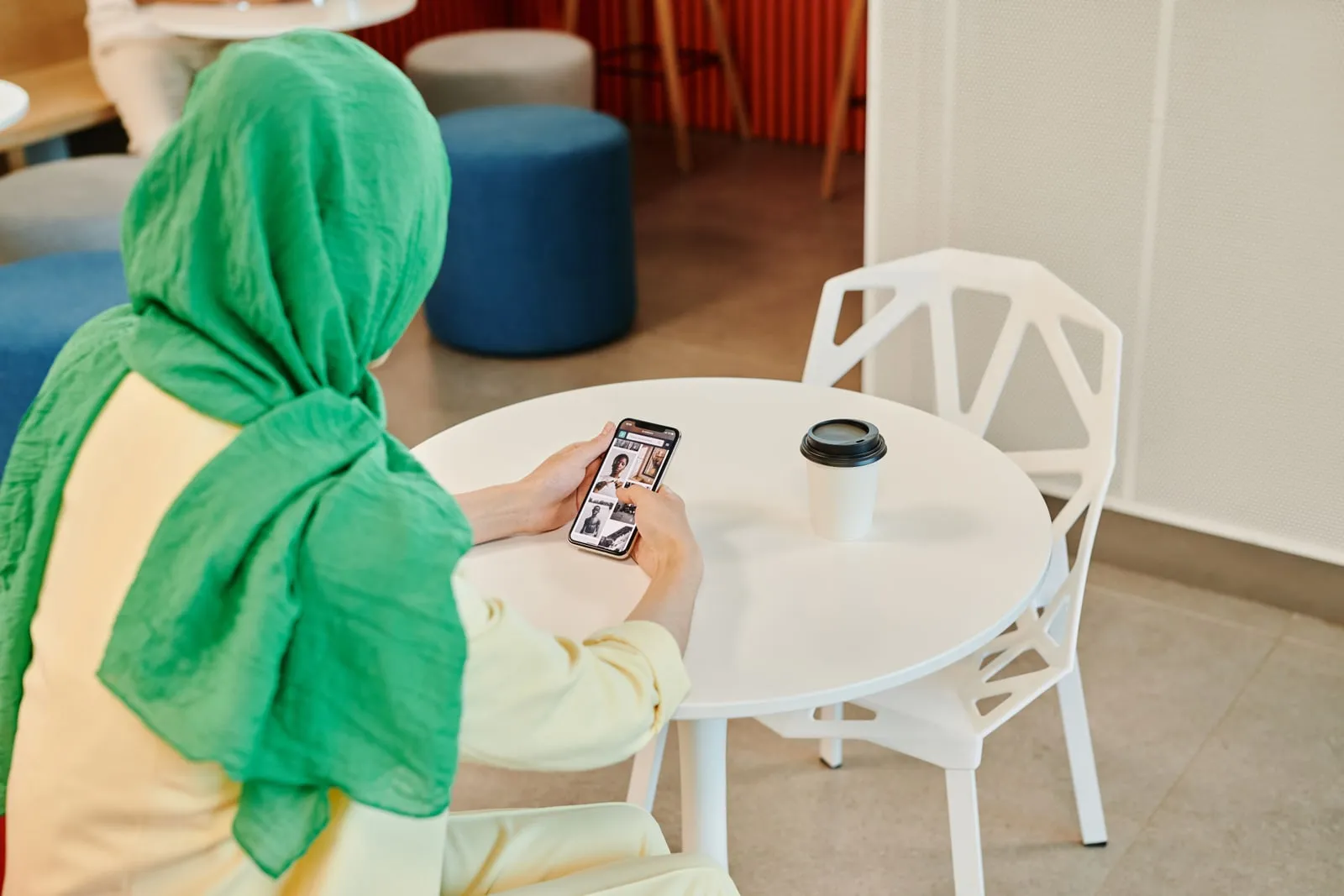 A person scrolling on a phone at a cafe table