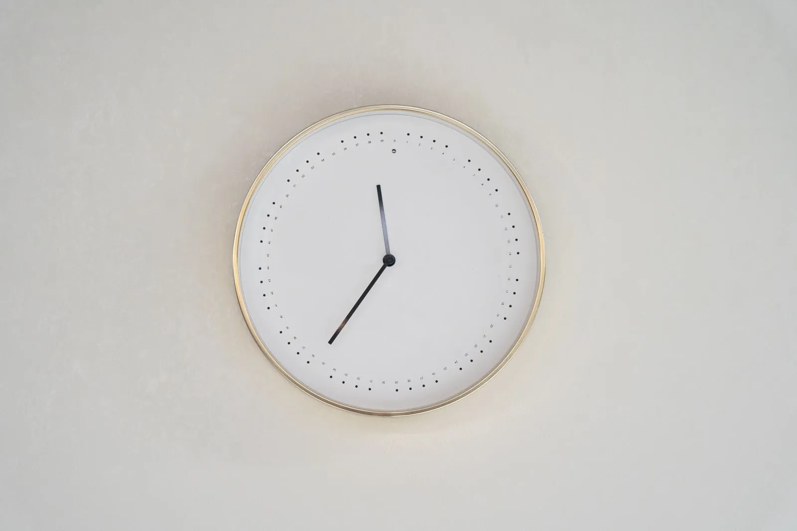 An analogue wall clock on a plain white wall