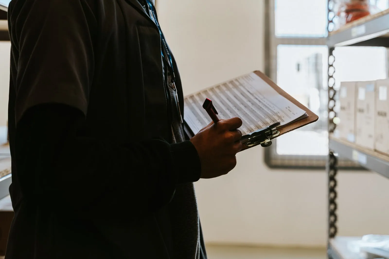 A person writing on a clipboard inside an industrial facility