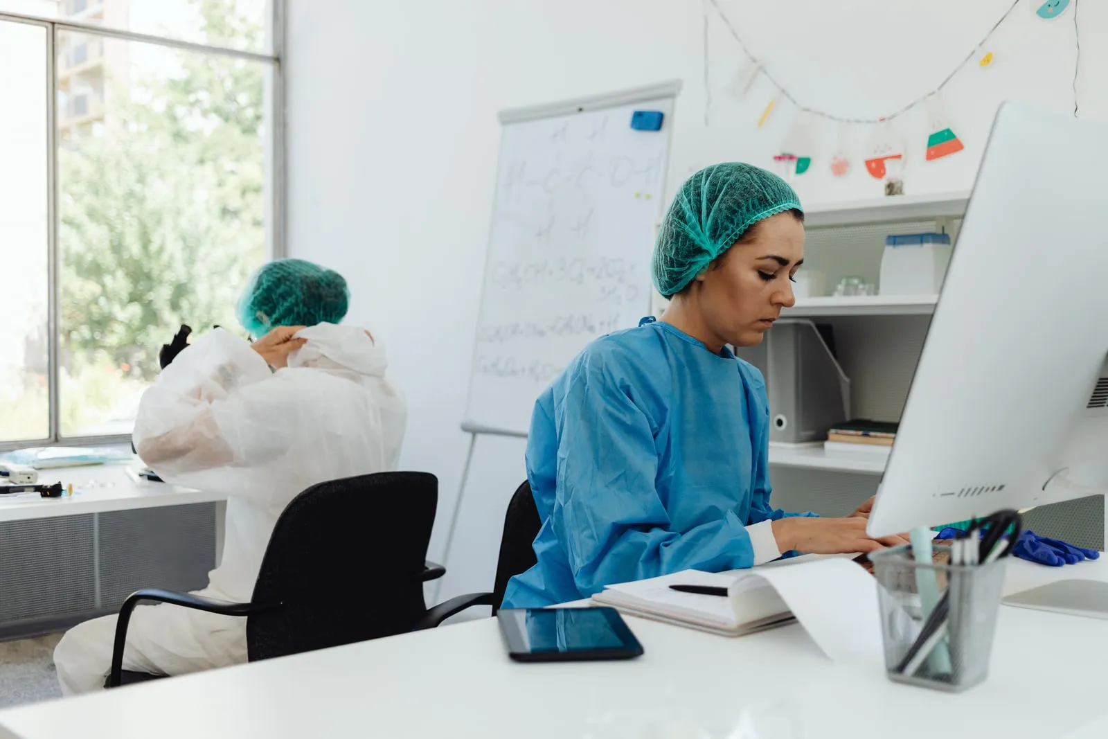 Duas investigadoras de bata de proteção a trabalhar num computador num laboratório
