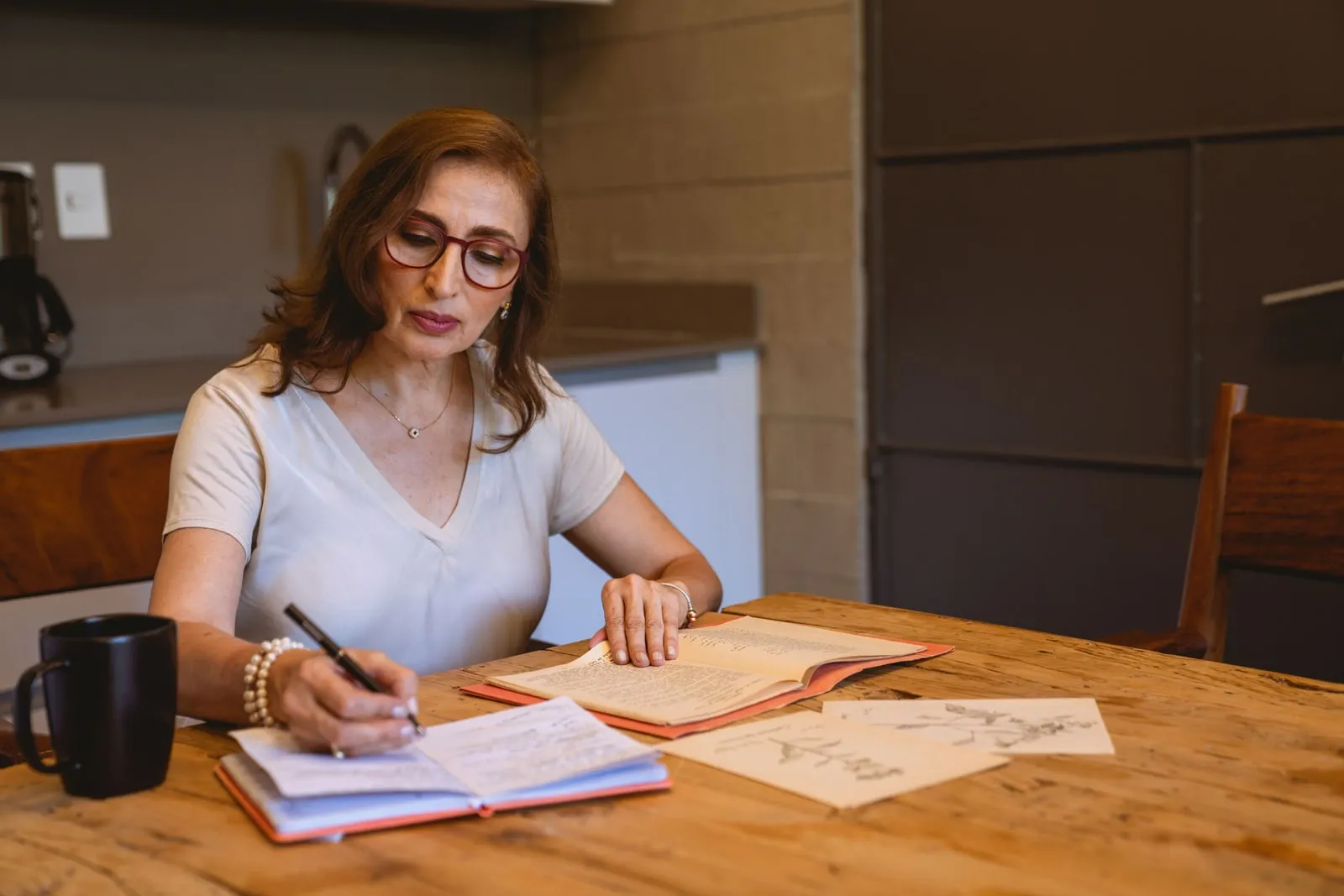 A person writing in a notebook at a kitchen table