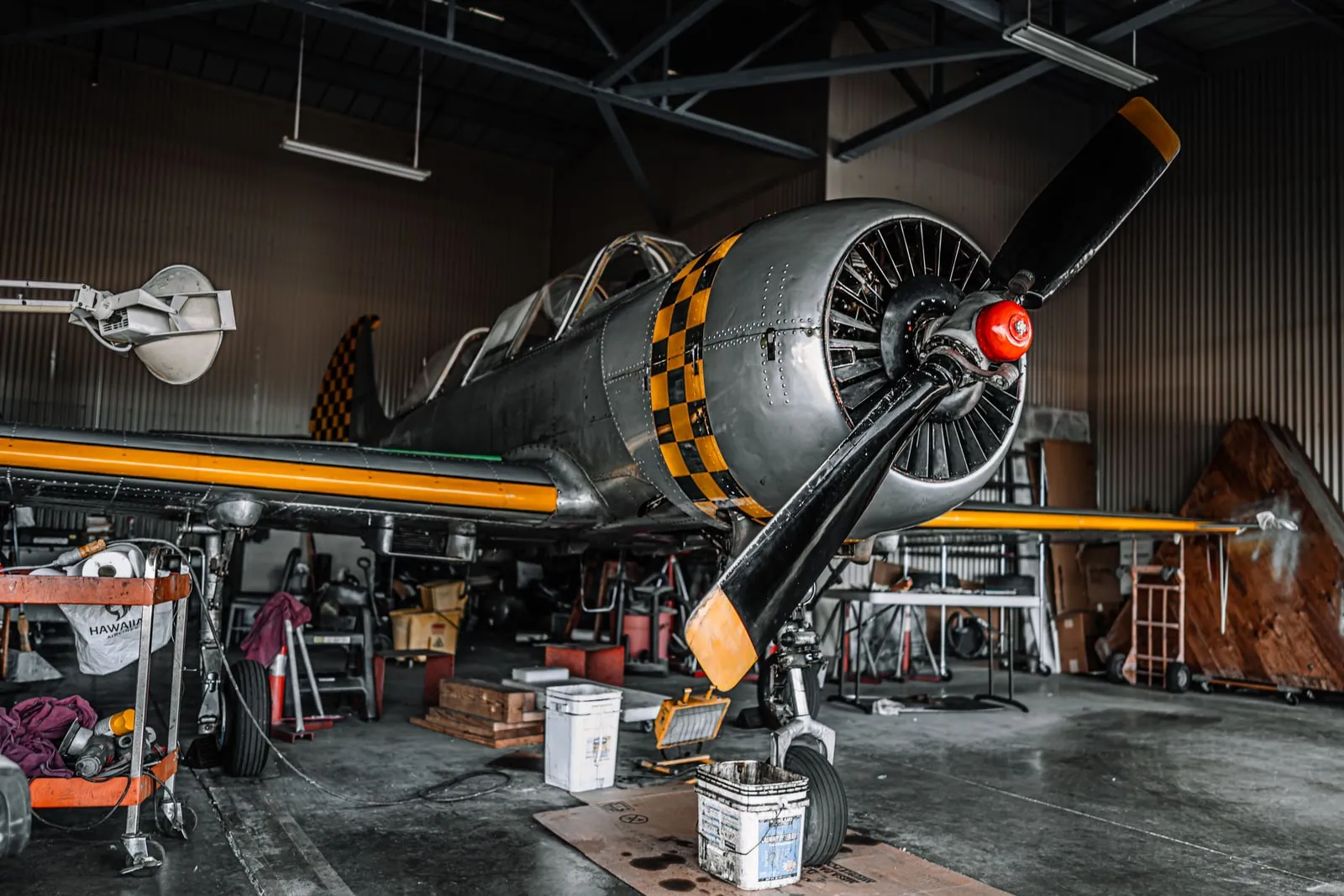 A vintage propeller aircraft undergoing maintenance in a hangar