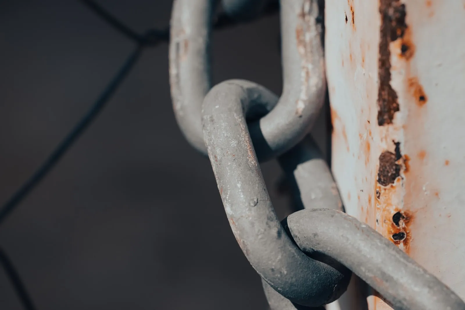 A close-up of heavy chain links against a rusted post