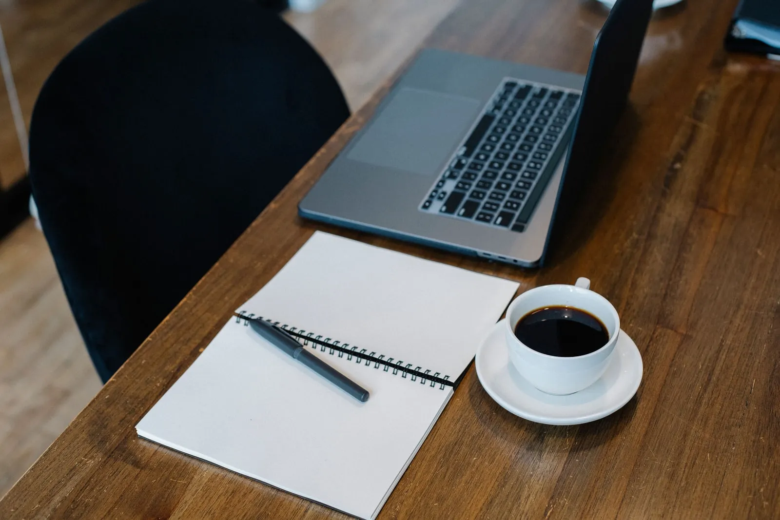 A laptop and notebook on an office desk
