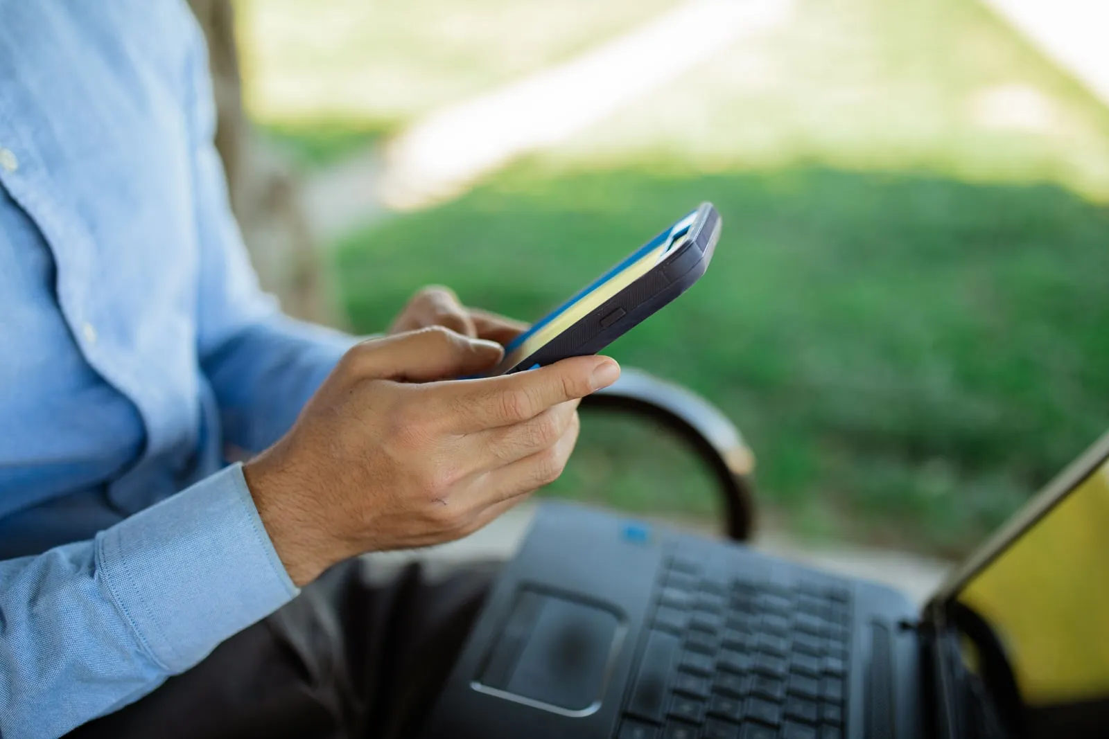 A person using a laptop and a phone side by side
