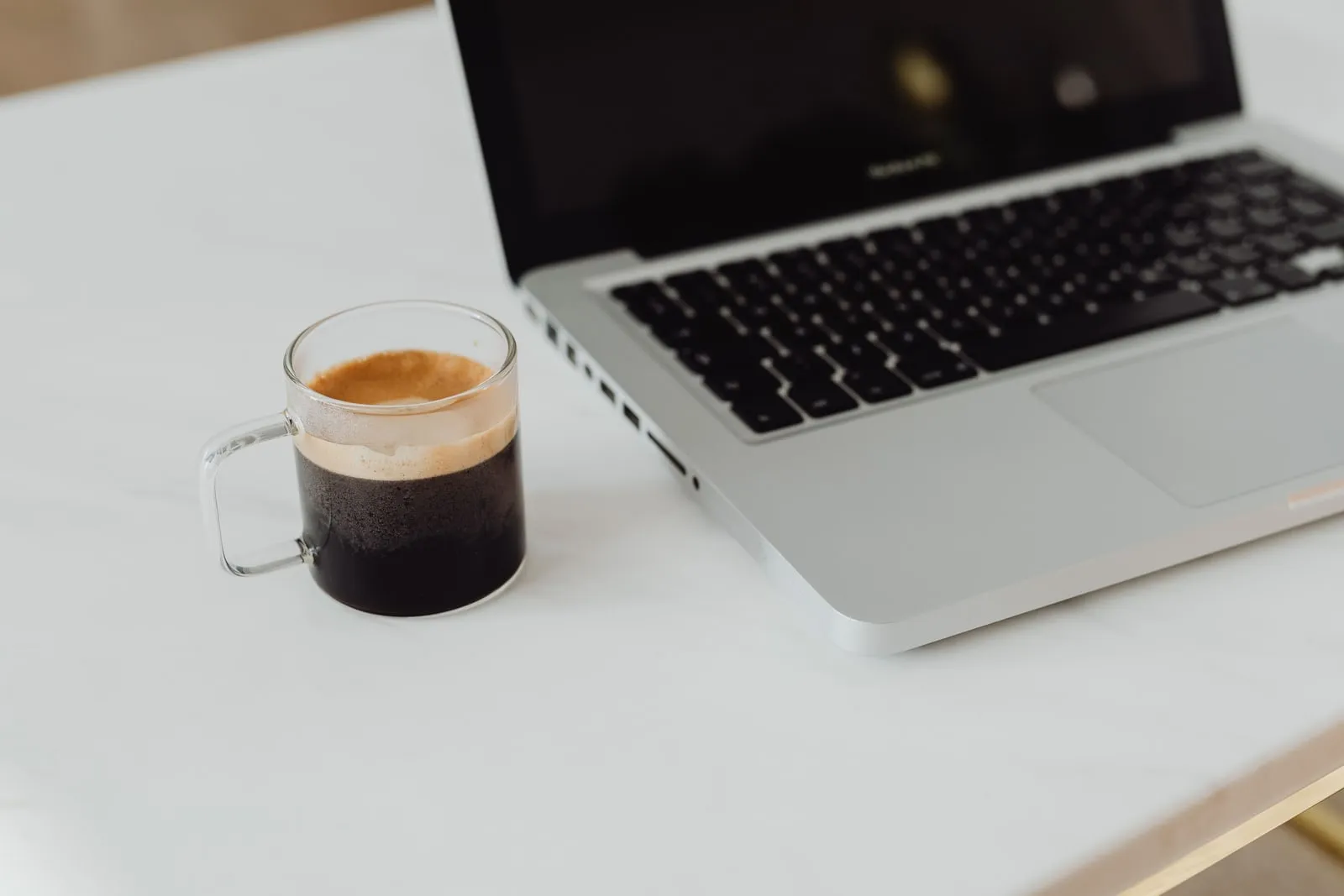 An open laptop on a desk beside a coffee cup