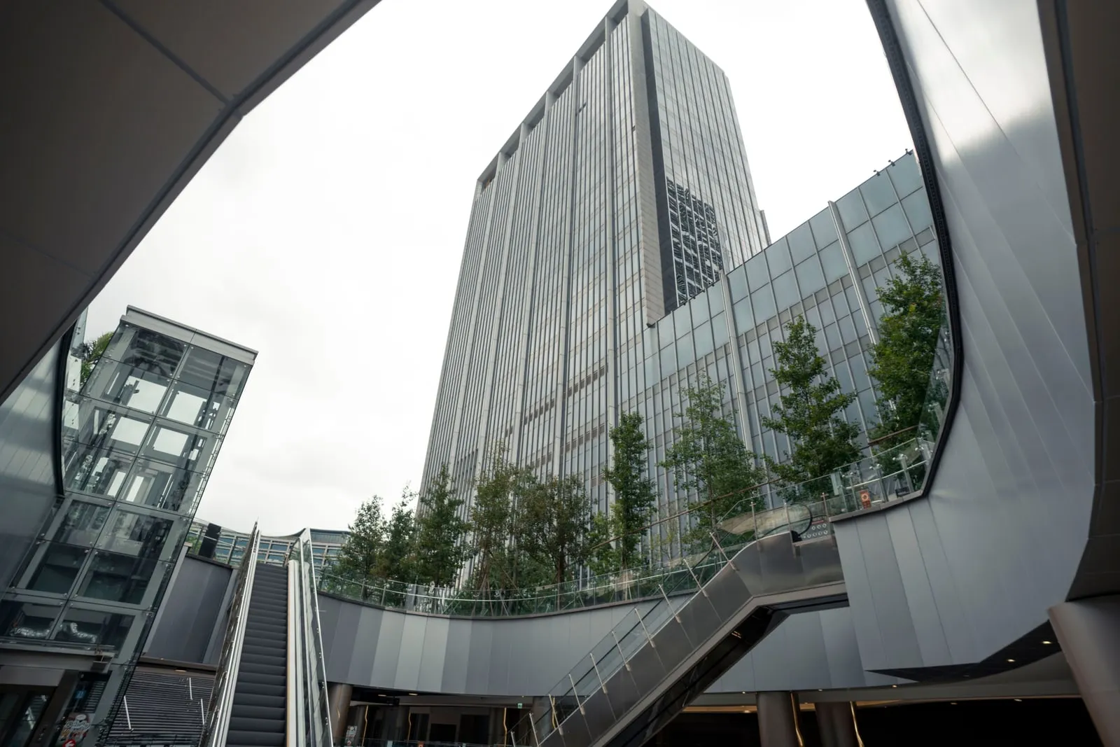 An office tower seen from the plaza below, with escalators in the foreground