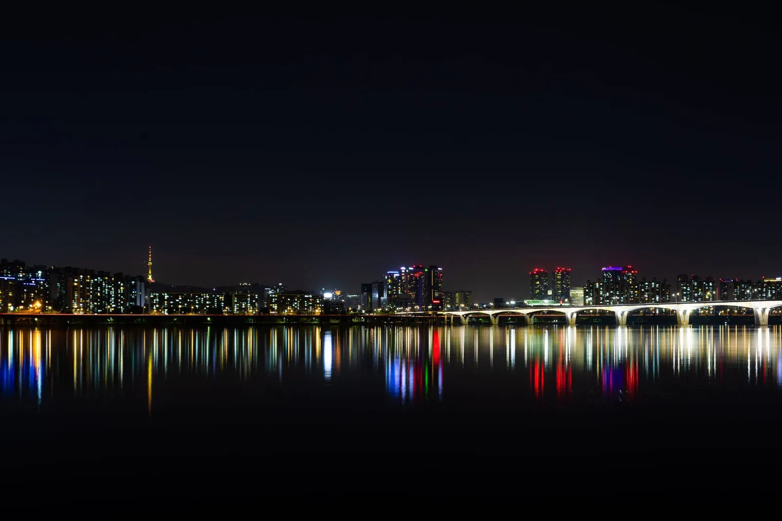 The Seoul skyline at night reflected in the river below