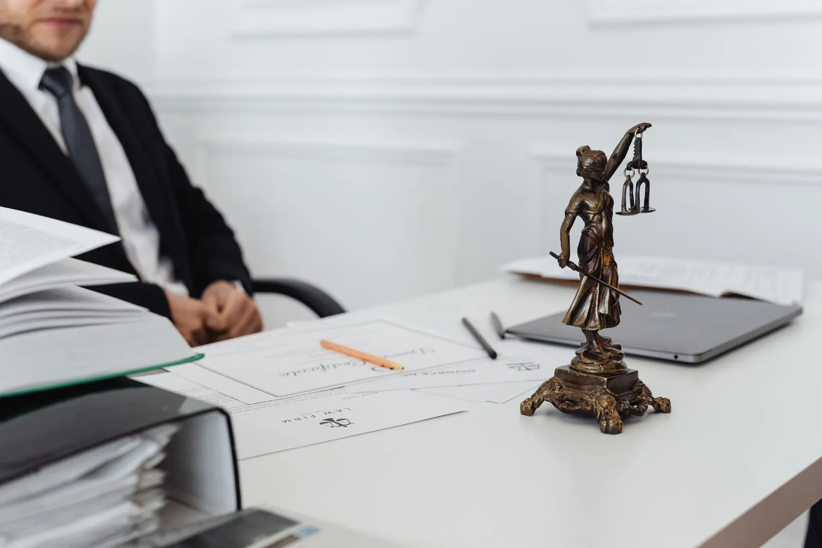 A figure of Lady Justice on a desk beside documents
