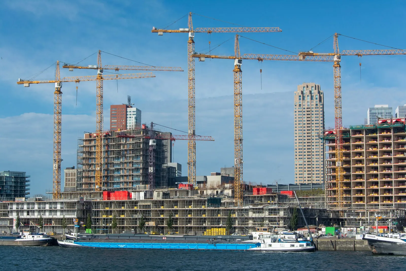 Construction cranes over a building site by the water