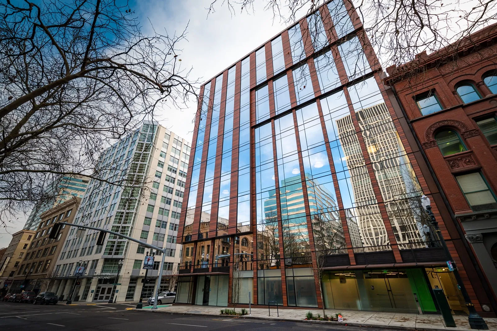 En kontorbygning med glasfacade i en gade under en blå himmel