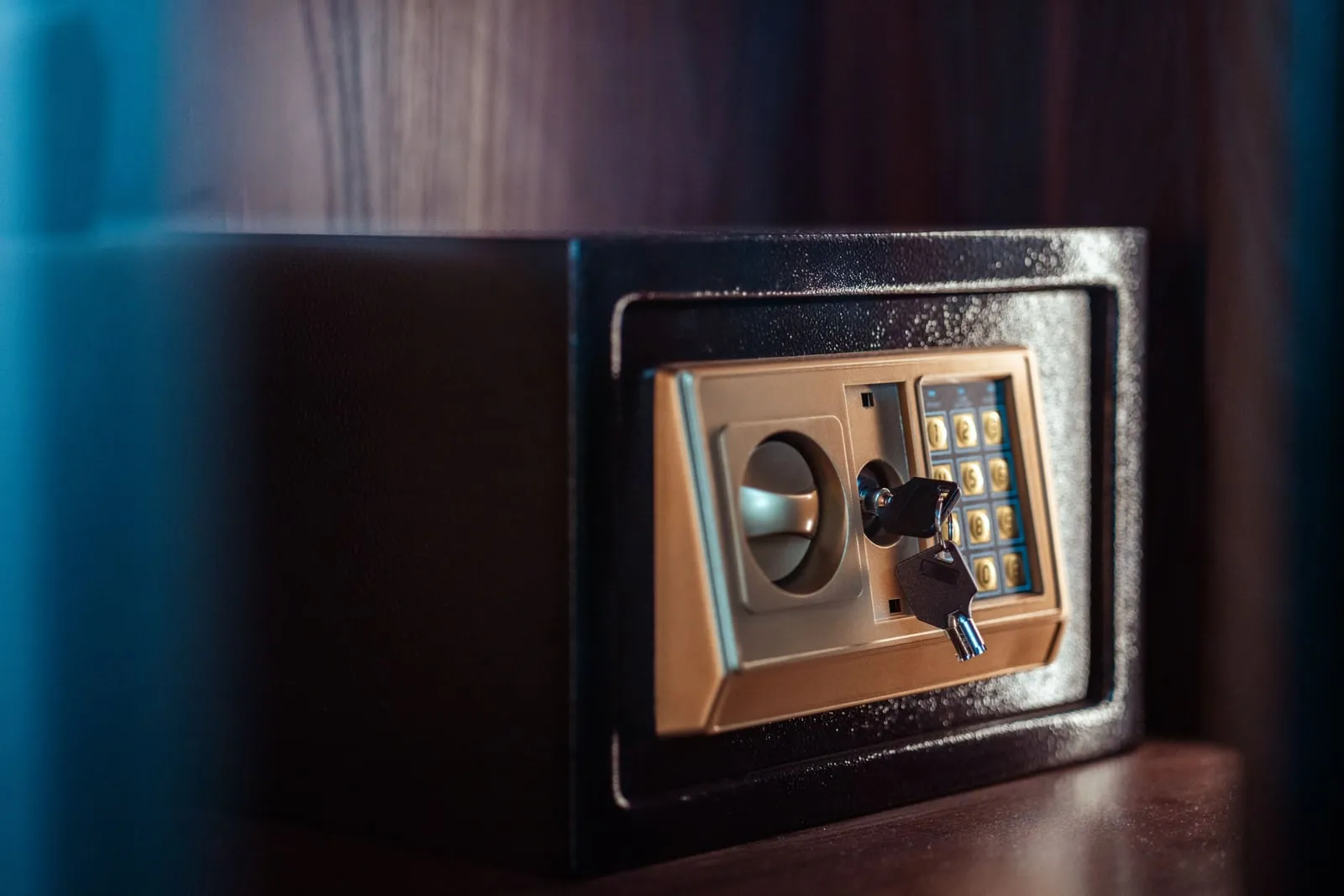 A small safe with a keypad and a key in the lock