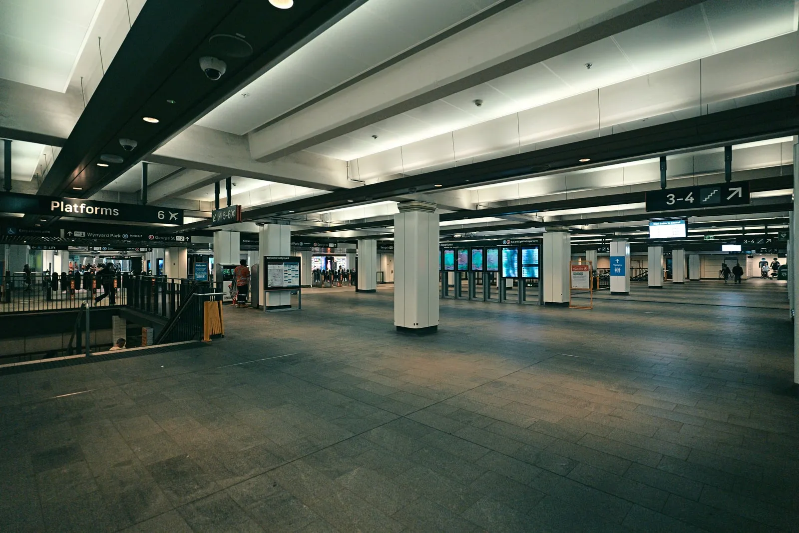 A railway station concourse with ticket gates and departure boards