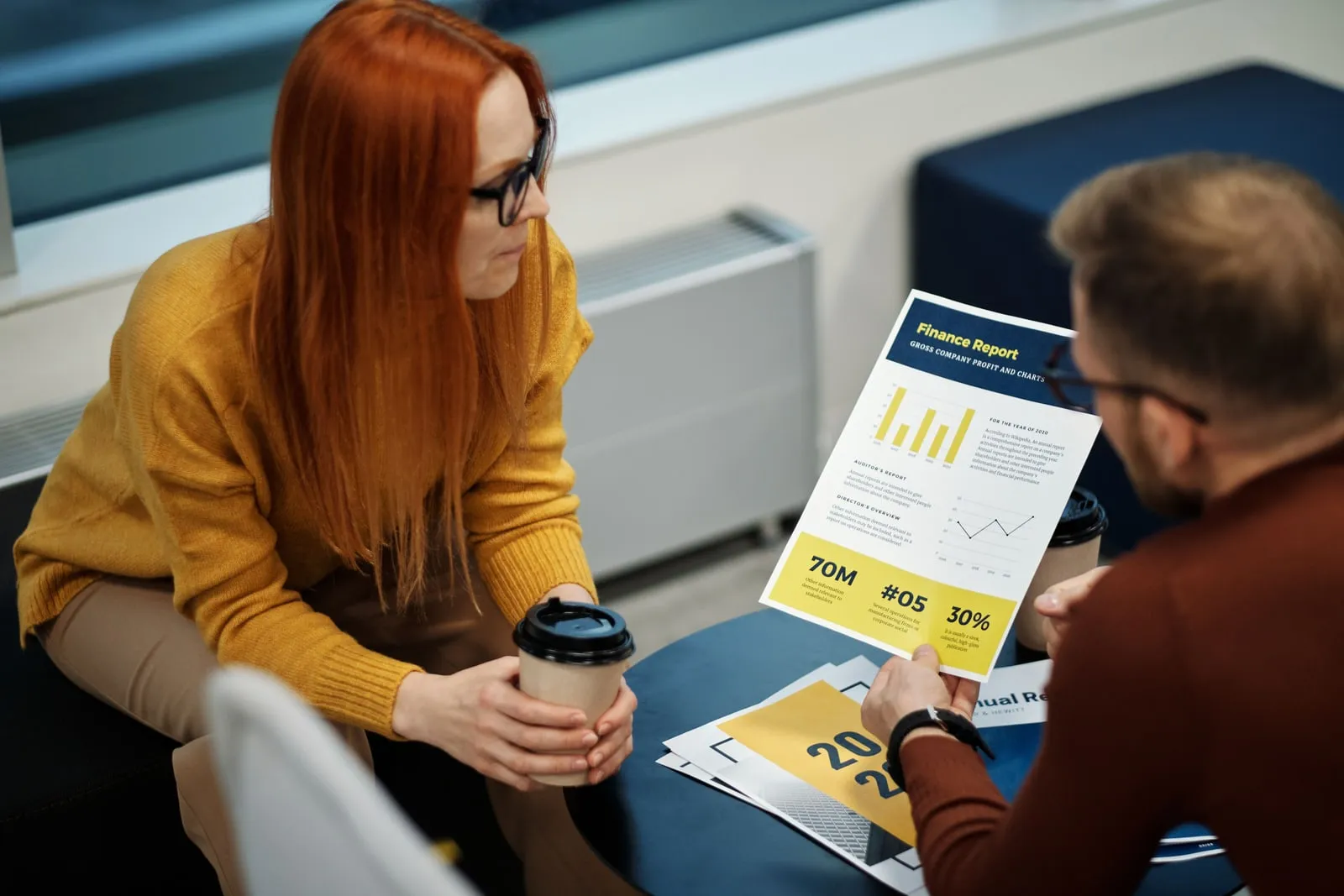 Two people reviewing printed documents at a conference table