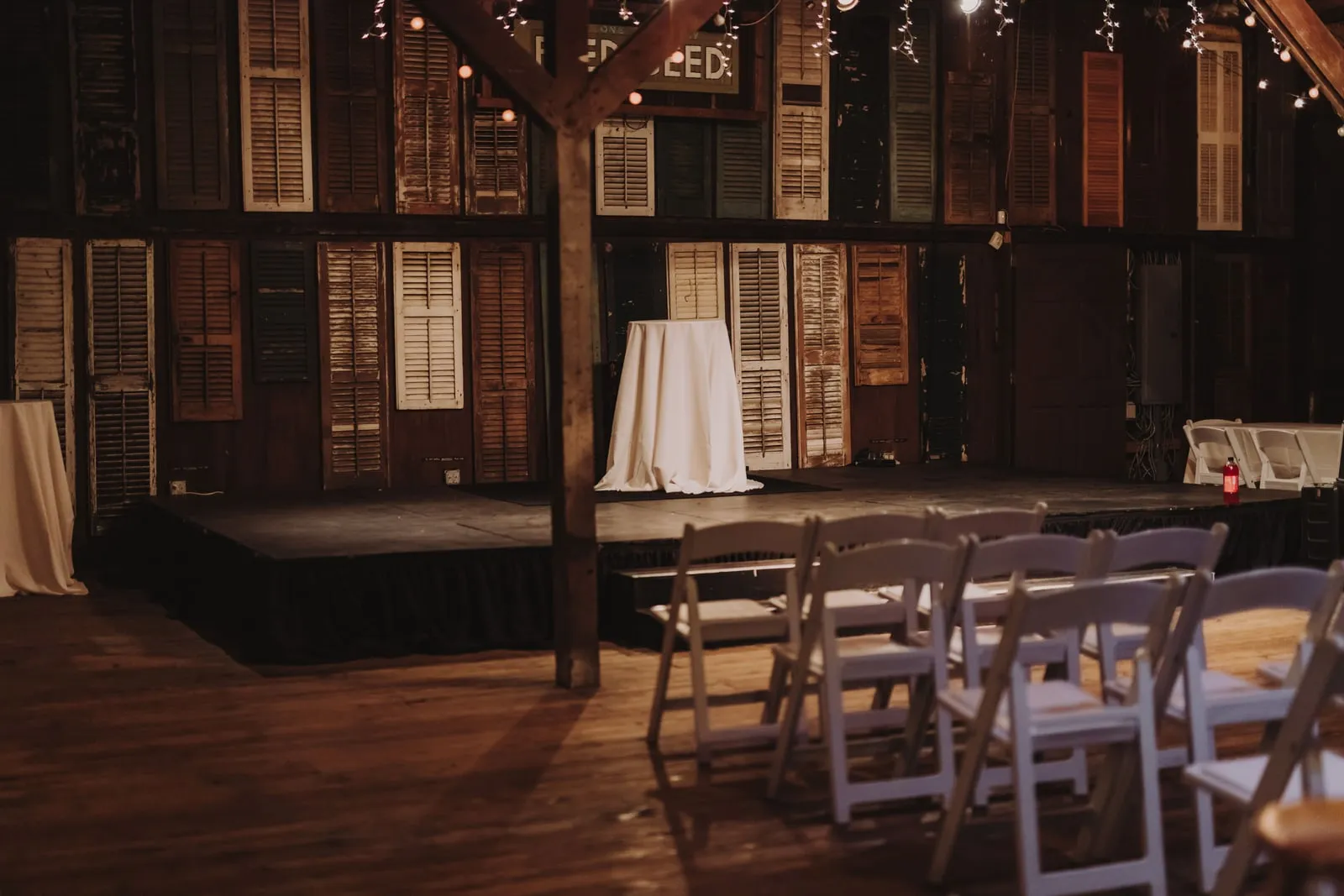A small stage with a cloth-covered table and rows of folding chairs