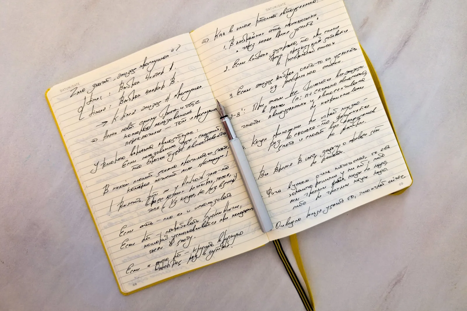 An open notebook of handwritten notes beside a pen on a desk