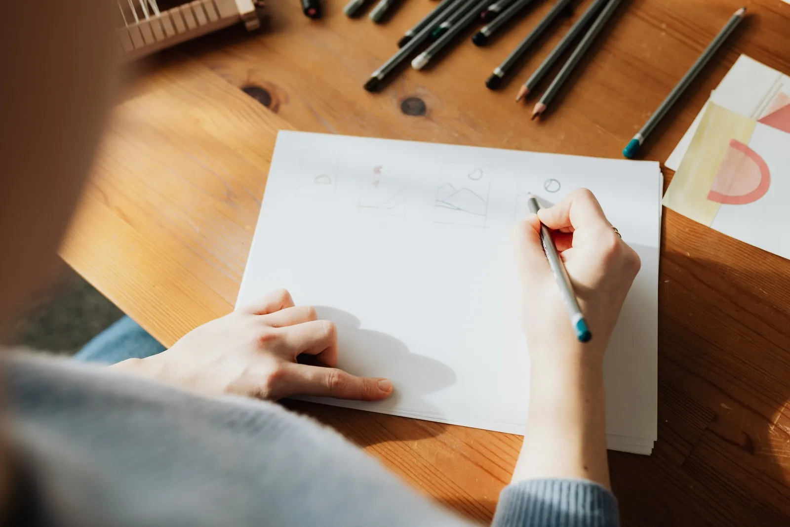 A designer drawing wireframes on paper with a pencil