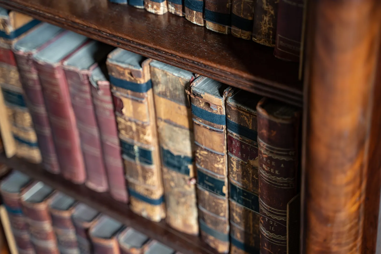 Rows of old leather-bound books on a wooden shelf