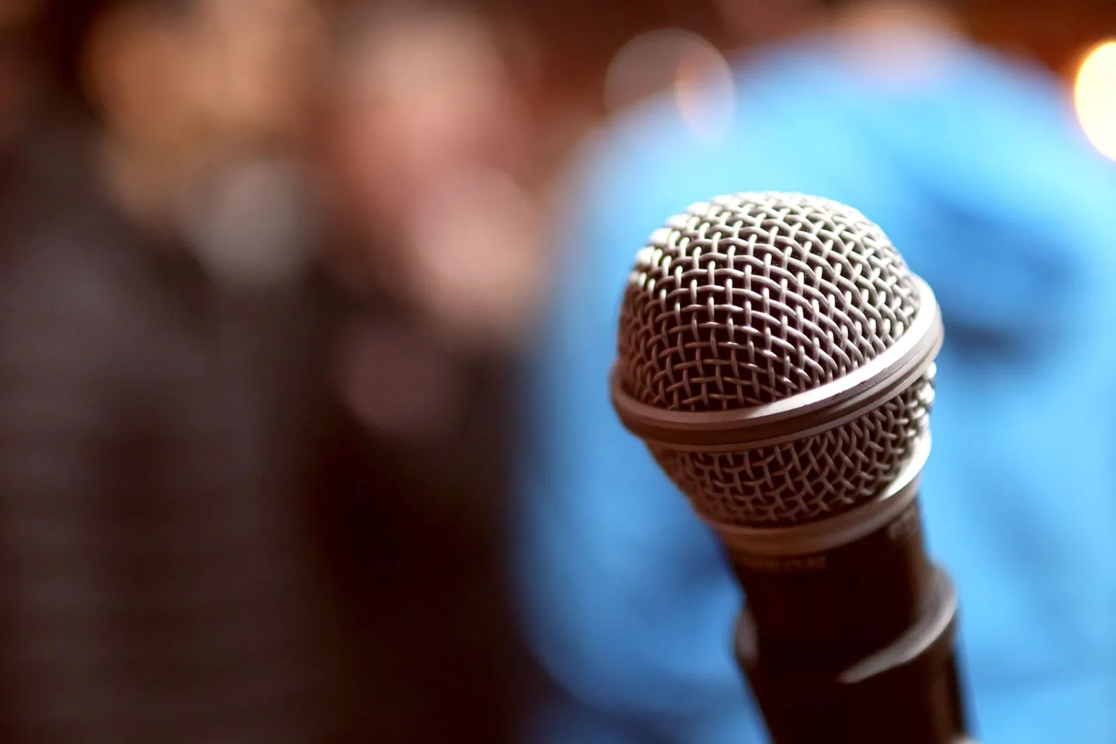 Close-up of a microphone in front of a blurred audience