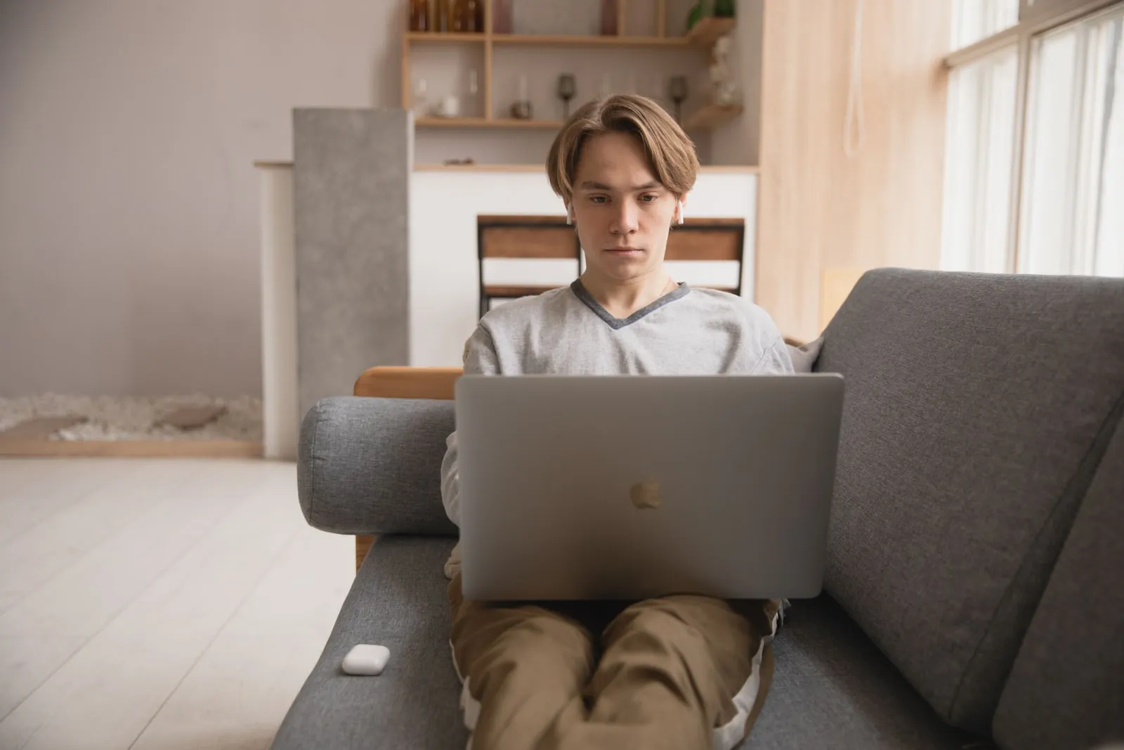 A young person sitting on a sofa at home with a laptop
