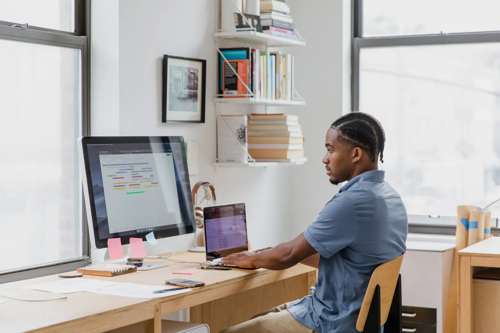 A person working at a desk with two monitors in a bright office