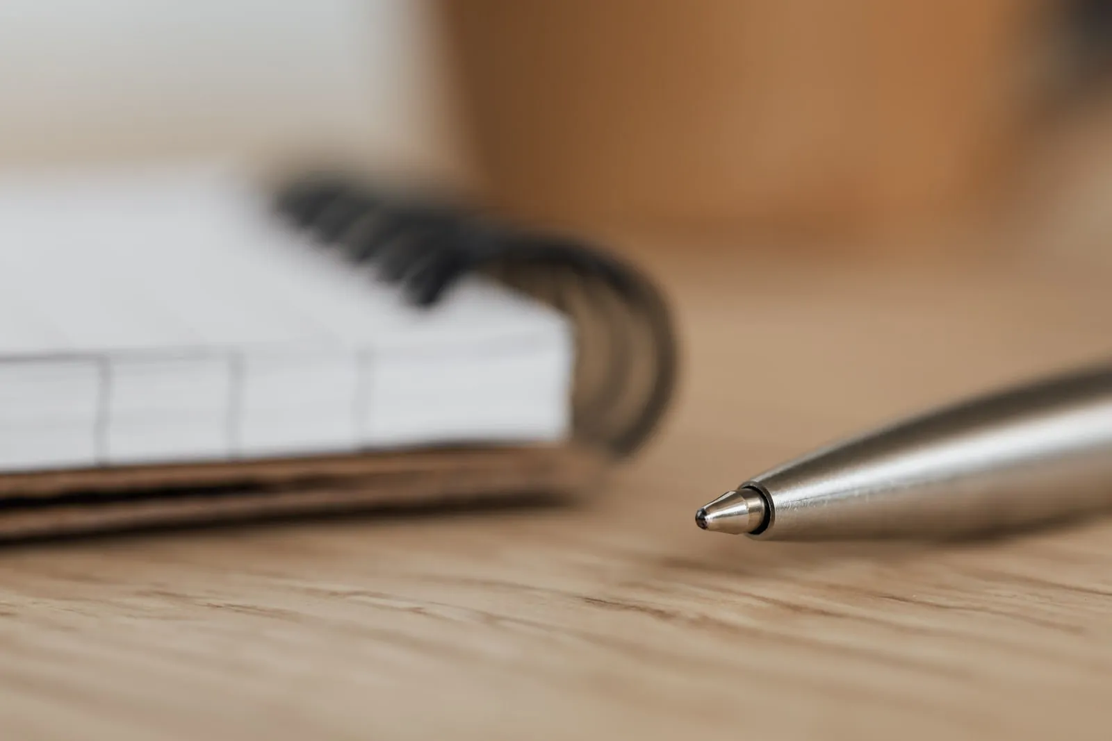 An open notebook and a pen on a wooden desk