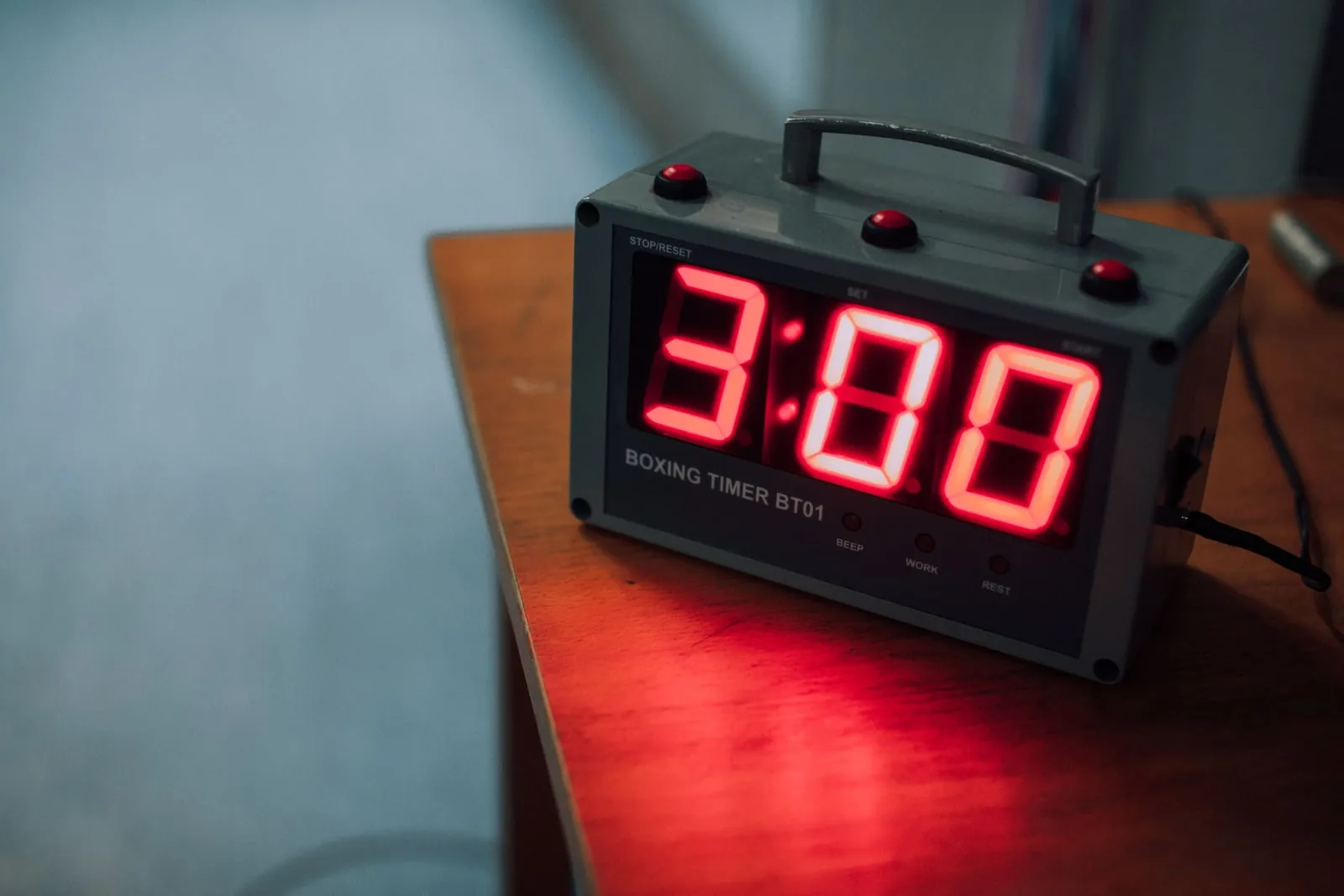 A digital countdown timer showing three minutes on a wooden table