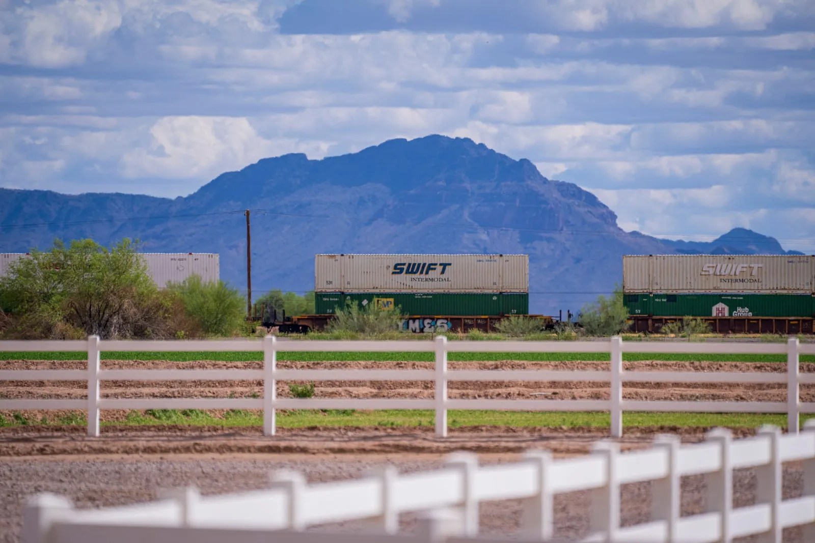 A freight train carrying stacked containers through open country