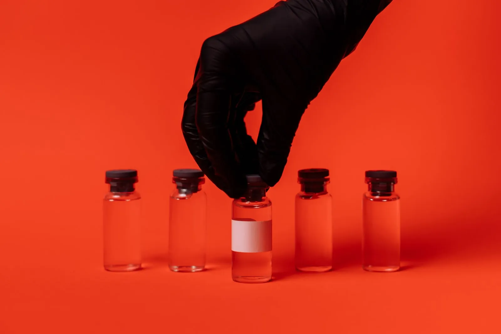 Gloved hands holding a small vial