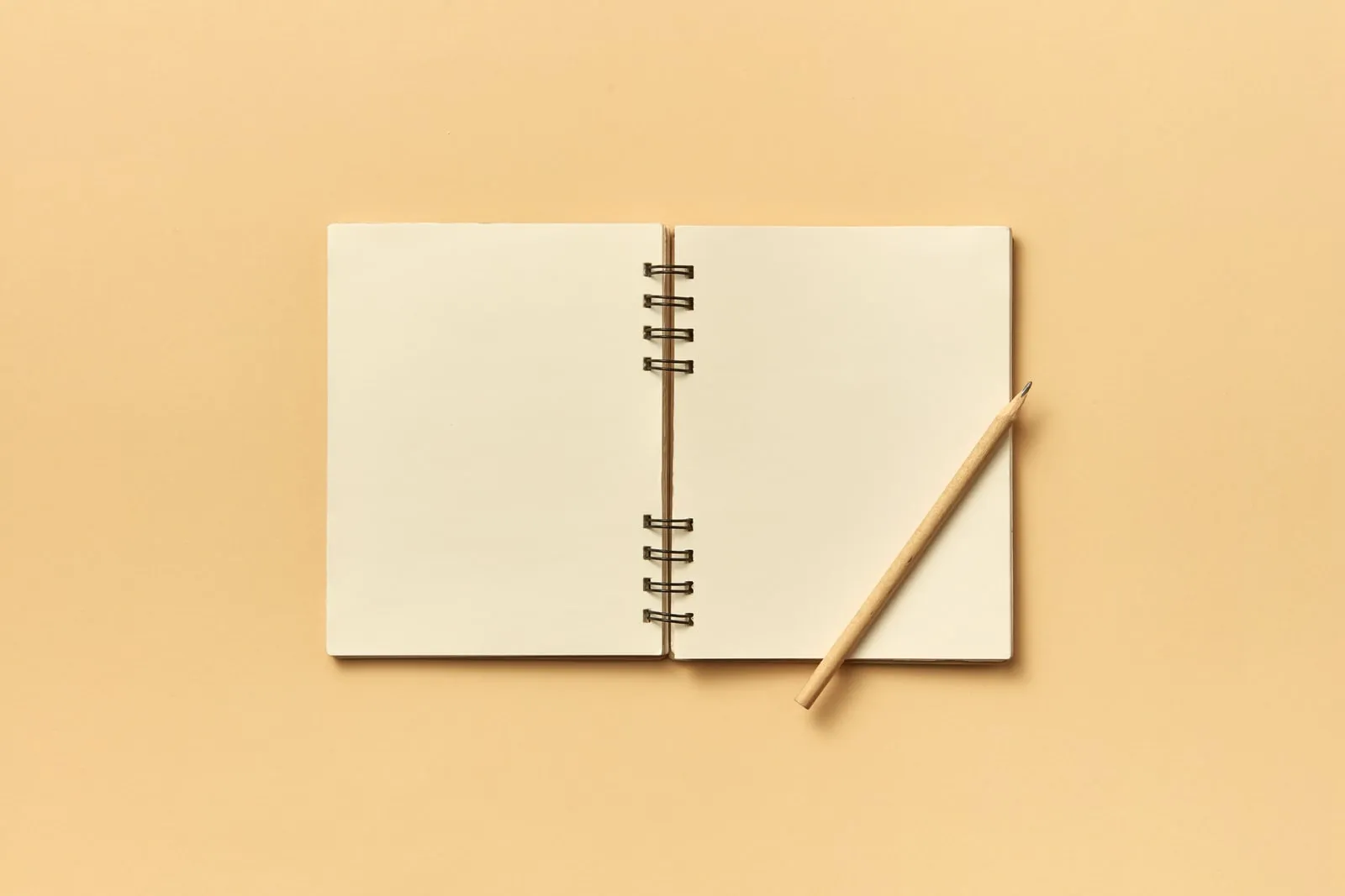 A blank notebook page and a pencil on a desk