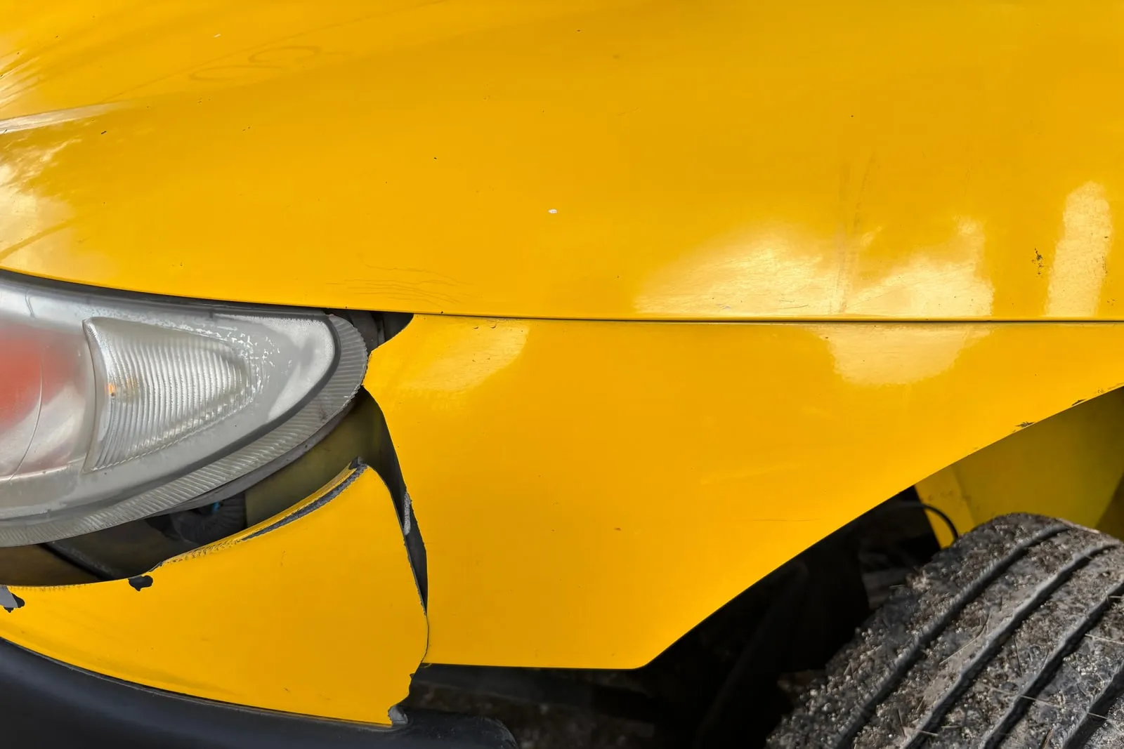 A damaged yellow car wing above a cracked bumper