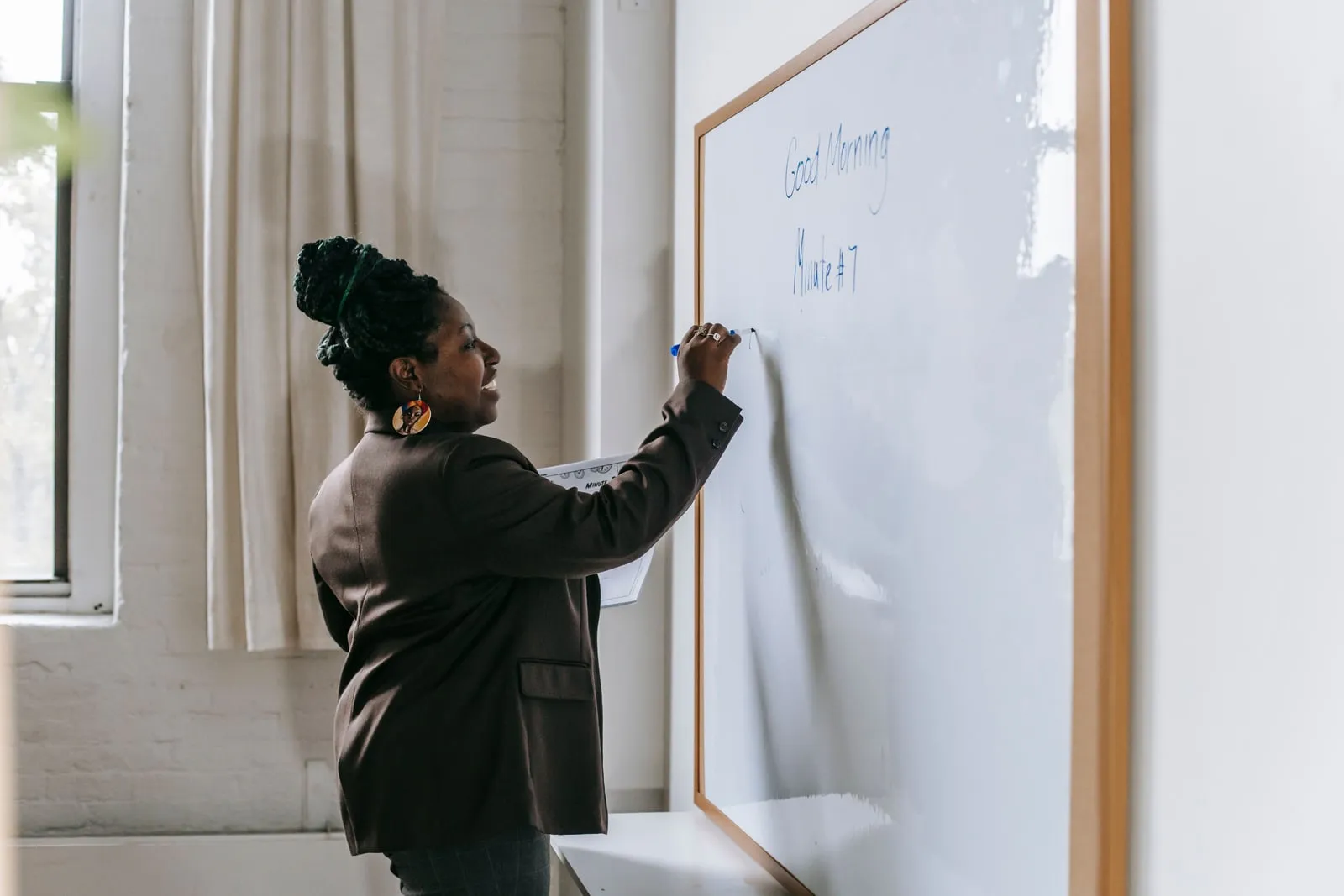 A teacher writing on a whiteboard in a classroom
