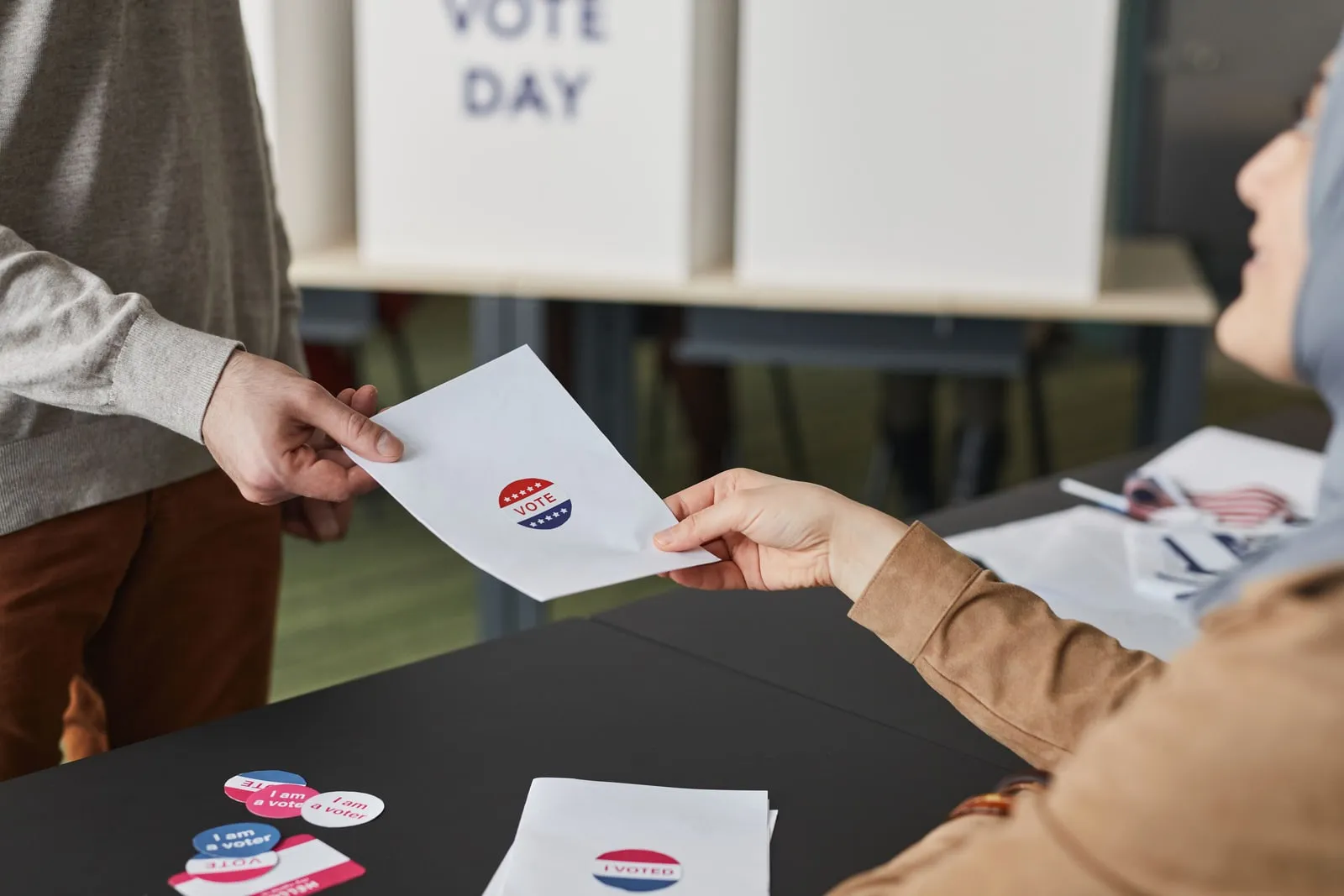 A ballot paper being handed across a polling station desk